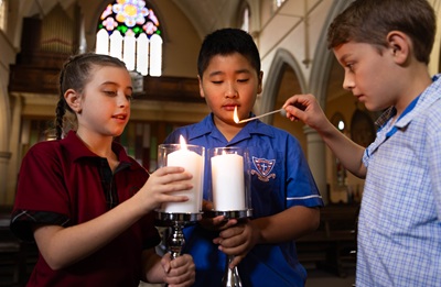 Students in a church lighting prayer candles
